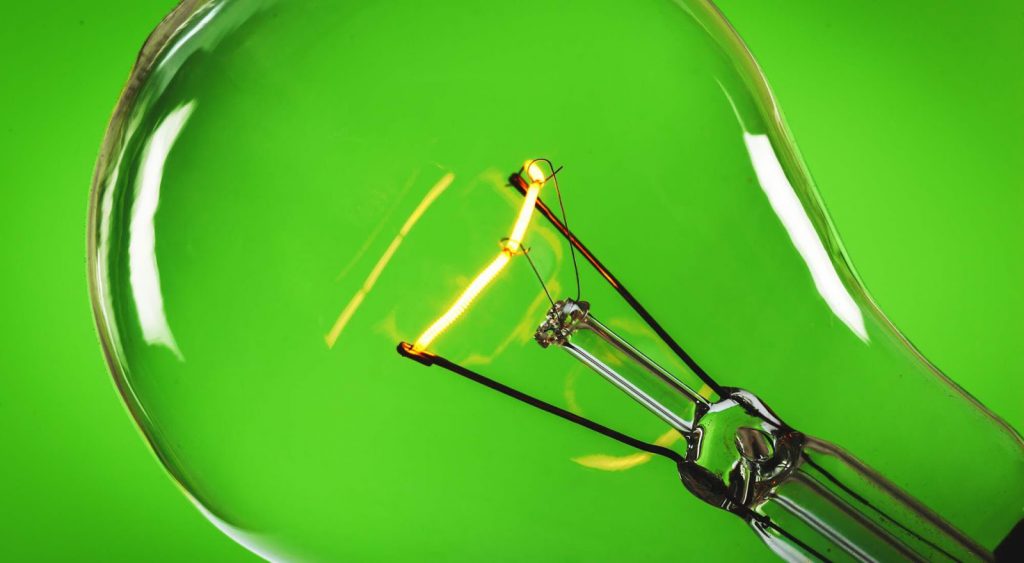 Lightbulb against green background. Power Wizard can light the way to the best Abilene Electricity plans.