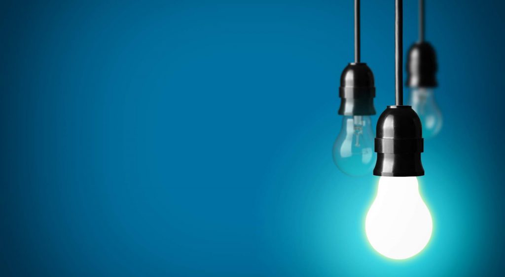 Lightbulbs hanging against blue wall. Electric Companies In Central Texas