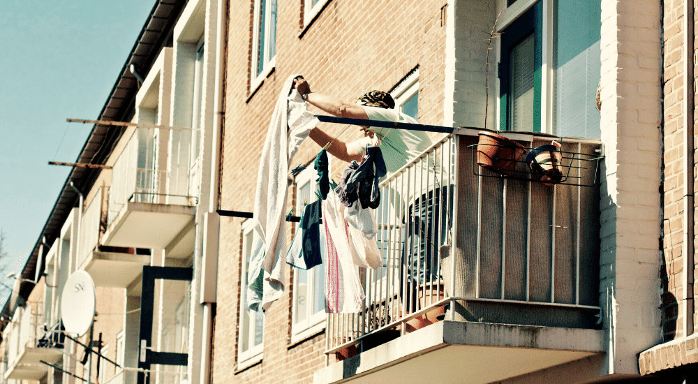 Woman drying laundry - How To Save On Heating Costs In Apartment
