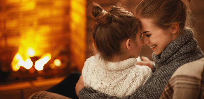 Mother and daughter in front of fire - How To Save On Heating Costs In Apartment
