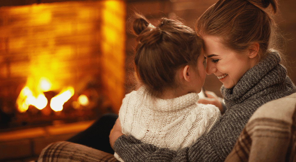 Mother and daughter in front of fire - How To Save On Heating Costs In Apartment
