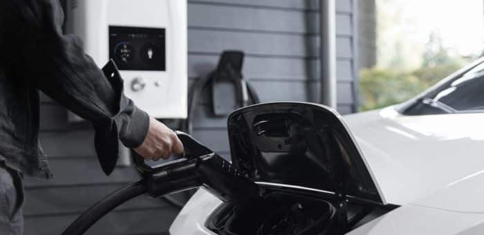 someone plugging in an EV vehicle at a charging station