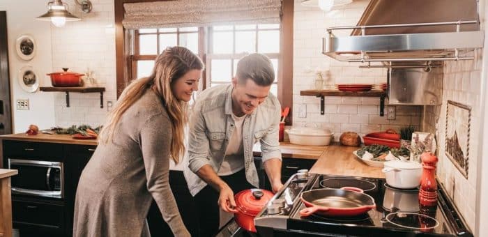 A woman and man putting a dish in the oven in a beautiful kitchen