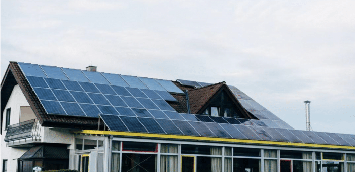 A large building covered in solar panels with a background of a cloudy sky