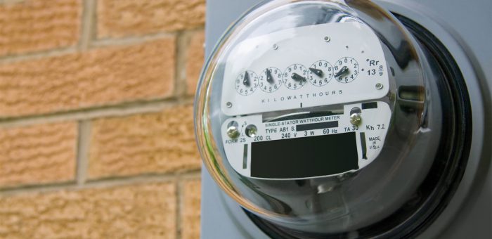 an eye-level photograph of an electrical meter on a brick wall